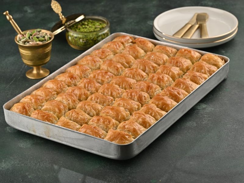 Tepsi içinde fıstıklı baklava, yanında dövülmüş Antep fıstığı